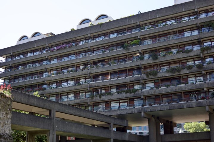 A ground-level shot looking up at one of the buildings at the Barbican estate, showing 6 floors of balconies full of plants.
