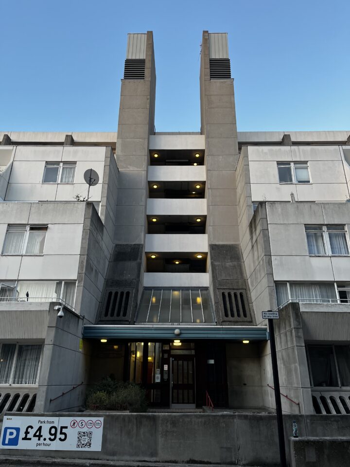 A detail photo of the Brunswick Centre, showing two concrete columns rising a few metres above the top storey of the building. They appear to be used for cooling, with vents in the top section of the column.