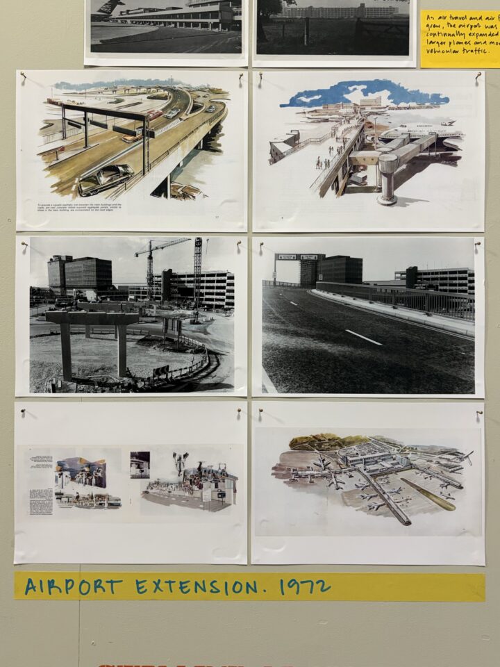 A display board shows six architectural drawings and photos of an airport extension. Some images are sketches of roads and terminals, others are black-and-white construction photos or site plans. A yellow label reads AIRPORT EXTENSION. 1972 at the bottom.