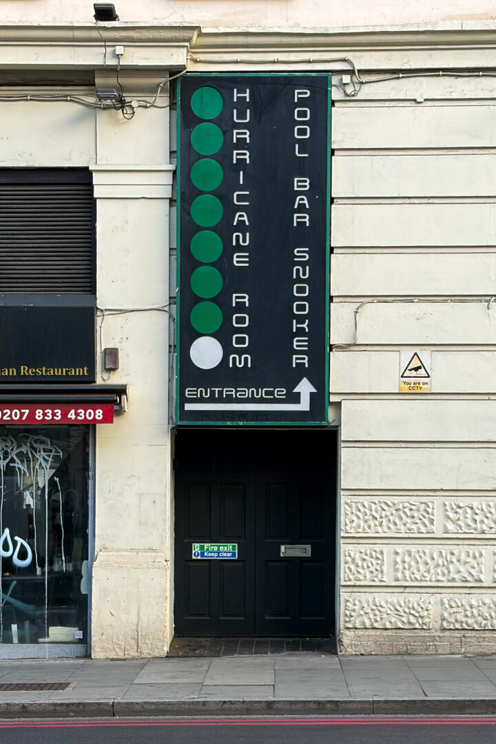 Vertical sign over a black door reads Hurricane Room Pool Bar Snooker with six green dots and one white dot. There’s an arrow pointing right at Entrance. A “For Sale” sign is on the door. A warning notice is on the wall above right.